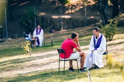 Unos jóvenes se confiesan con sacerdotes en el campamento de verano de LifeTeen, al aire libre