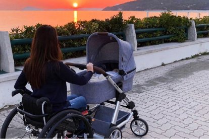 Laura Miola pasea con la puesta de sol, con su silla de ruedas y el carrito del bebé