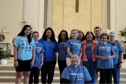 El padre Damian, agachado, con parroquianos, en la fiesta de Santa Mónica, 27 de agosto, en la parroquia del mismo nombre en Toronto