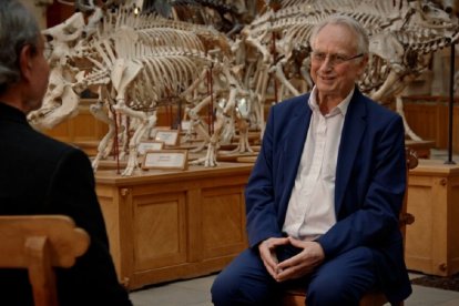 Richard Dawkins rodeado por esqueletos em um museu de paleontologia.