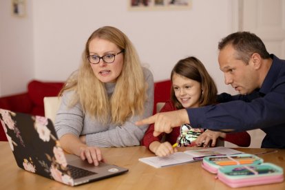 Un padre y una madre ayudan a una niña con un ordenador portátil... los padres deben orientar y limitar el uso de las pantallas