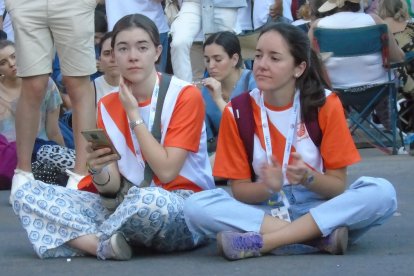 Dos jóvenes voluntarias descansan tras horas de servicio, pero en su puesto, poco antes de llegar el Papa
