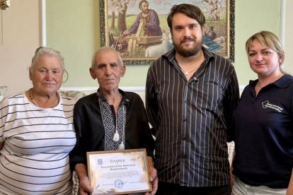 Yaroslav Banakhovsky com sua família e um diploma municipal recebido por sua atitude prestativa.