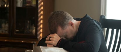 Un hombre se derrumba sentado leyendo la Biblia.
