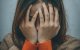 Chica joven se tapa la cara, triste.