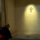 Un cardenal reza ante la tumba de Francisco, con su nombre y una rosa blanca depositada encima.