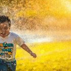 Niño jugando en el agua de un aspesor.