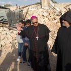 El patriarca católico Fouad Toual, con unos niños árabes y un clérigo armenio, junto a las ruinas de la casa derruida en terreno del Patriarcado