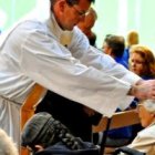 Un sacerdote ora por unas enfermas en silla de ruedas... forma parte de la misión del sacerdote abrazar su vocación sanadora