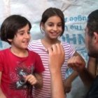 Unas niñas cristianas iraquíes desplazadas enseñan a contar hasta diez en árabe a un voluntario de CampamentoIrak