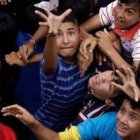 Los niños pobres de Guarambaré se esfuerzan por tomar al vuelo los billetes que tiran fieles desde el campanario