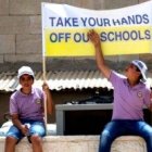 Dos jóvenes alumnos de las escuelas cristianas de Tierra Santa con una pancarta reivindicativa - Israel no está pagando lo comprometido