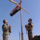 Dos soldados iraquíes colocan una cruz en lo alto de una iglesia en Bartella