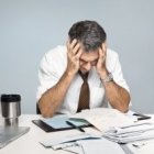 Un hombre agobiado ante las facturas que tiene que pagar