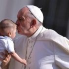 El Papa Francisco besa un bebé que le presentan en la audiencia del miércoles