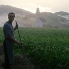 El personaje del beato Franz trabaja los campos desde la sombra... pero, más allá, el campanario y la luz apuntan al Cielo