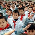 Escolares chinos en formación hacen el saludo comunista con su pañuelo rojo de pioneros comunistas