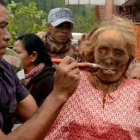 Un hombre da de comer a una pariente difunta, después de ponerle ropa nueva, en la famadihana de Madagascar