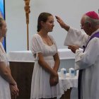 El obispo Breenan unge y confirma a 3 jóvenes revestidos con el blanco del bautismo... en el centro, Hayley, mencionada en el reportaje