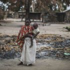 Una mujer con su hijo en brazos en un área quemada en la aldea de Aldea da Paz, en el distrito de Macomia.