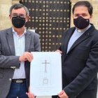 El presidente de la Agrupación de Cofradías, José Cabezas, y el párroco de Aguilar, Pablo Lora sostienen el boceto de la nueva cruz.