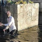 Un sacerdote ortodoxo rumano bautiza en un río irlandés al escrito inglés Paul Kingsnorth en 2021