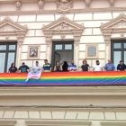 Autoridades del Ayuntamiento de Alcázar de San Juán y activistas homosexuales desplegando la bandera LGBT, bajo un cuadro del Sagrado Corazón de Jesús.