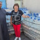 El padre Oleksander y una parroquiana de la parroquia de Berislav en Ucrania, en un reparto de agua