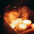 Una mujer joven con velas, quizá orando, en una foto de Harvey Robinson para Unsplash