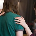 Unas mujeres oran intercediendo por otra con el gesto de imponer las manos