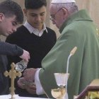 Dos jóvenes ayudan como monaguillos al Papa  Francisco en la misa en la Casa Santa Marta