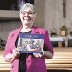 Christine Panyard muestra el libro que consagró a la Capilla Sixtina de Miguel Ángel. Foto: Detroit Catholic.