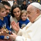 Francisco bendice una imagen del Niño Jesús al ser saludado por una familia presente en la audiencia. Foto: Vatican Media.