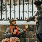 Una mujer da limosna a un hombre en la calle nevada.