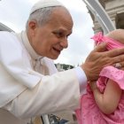 El Papa saluda a una bebé al hacer el tradicional recorrido de los miércoles por la Plaza de San Pedro.
