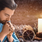 Un hombre rezando el rosario, en el marco de una corona de Adviento que prepara para la llegada de la Navidad.