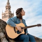 Una joven con guitarra, en un tejado, con un campanario, símbolo de tantos músicos que miran a Dios y quieren ser mirados por Dios