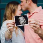 Una pareja muestra la ecografía de su bebé... en España hay un pequeño repunte de natalidad, que no compensa los fallecimientos