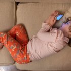 Niña con movil echada en un sofá