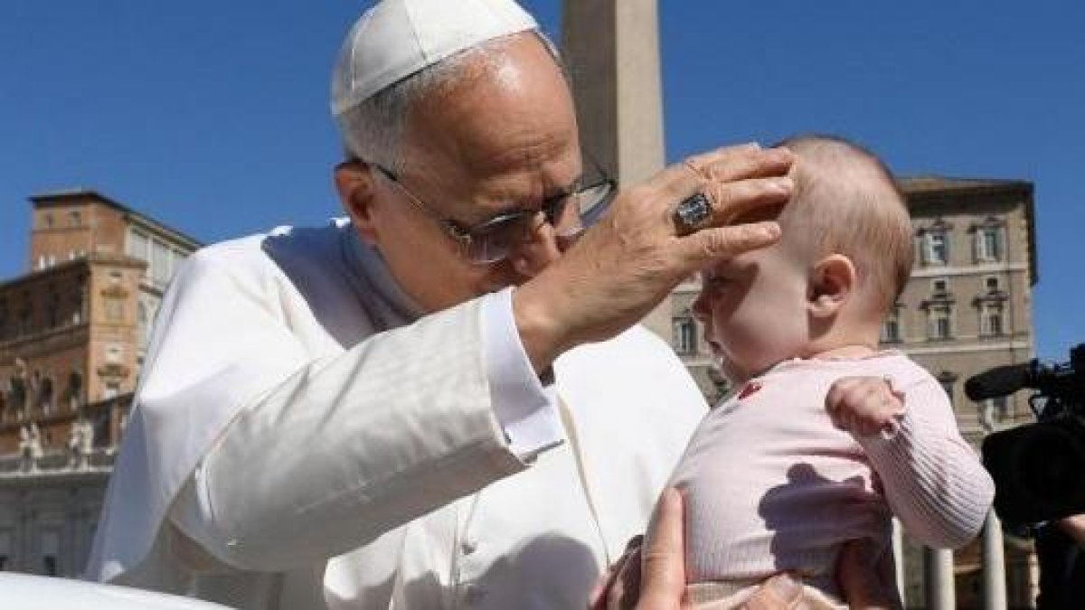 El Papa traza la señal de la Cruz sobre la frente de un bebé.