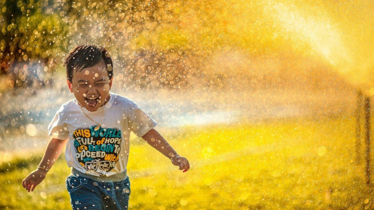 Niño jugando en el agua de un aspesor.