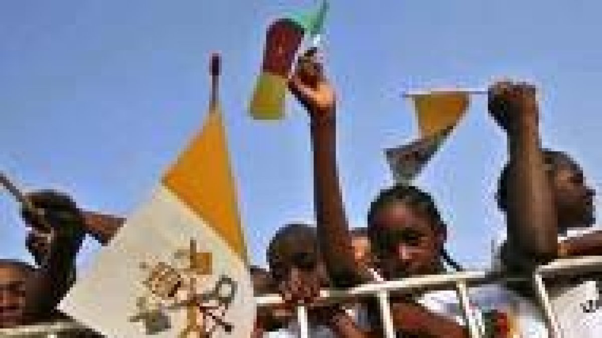 Unos niños africanos portan banderas del Vaticano