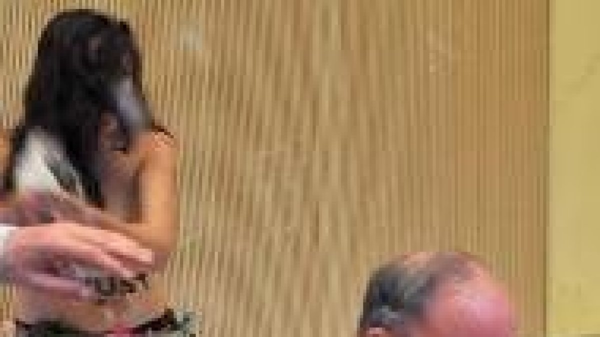 La agresora echa agua al obispo, mientras él reza