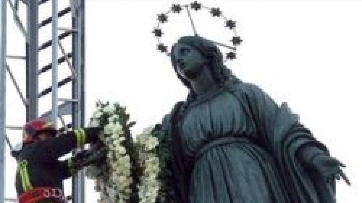 Un bombero de Roma deposita una corona de flores en lo alto del monumento a la Inmaculada