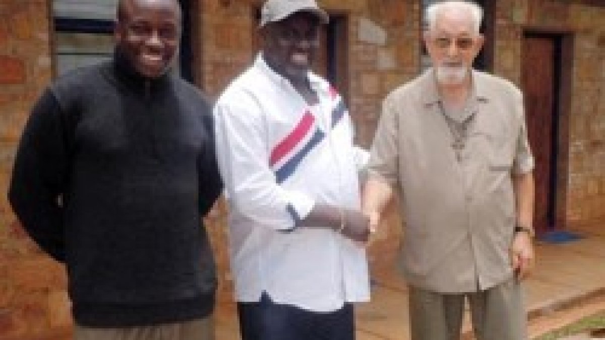 El padre Bernard Lesay con colaboradores de Action Batwa y unos libros y cuadernos para los niños del lugar