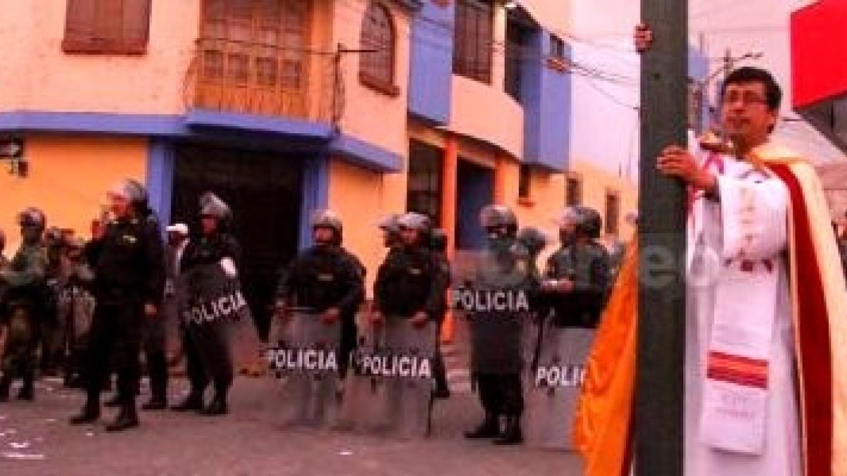 El párroco José Caselli Sandoval, cruz en mano, entre mineros manifestantes y policías en Islay, Cocachacra