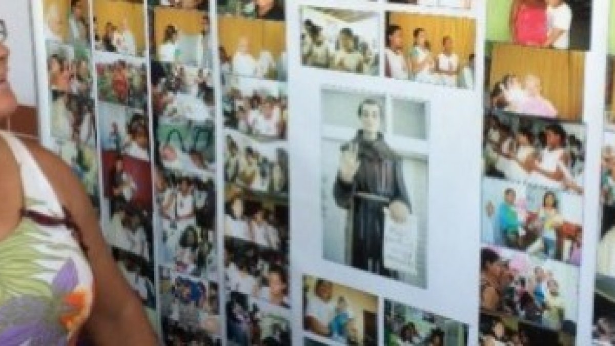 Doris Hipólito contempla el mural con fotos de niños salvados, con una imagen del popular San Frei Galvao en el centro