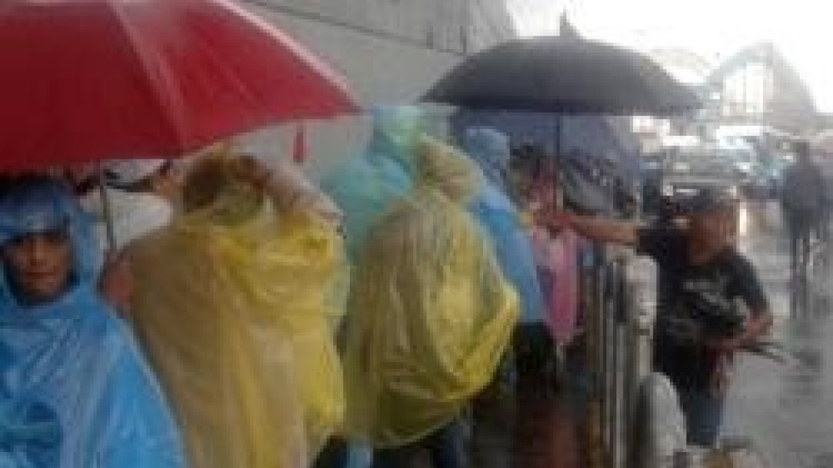 Los fieles esperan bajo el granizo y la lluvia para entrar en el espacio que acogerá la misa de Francisco en Quito