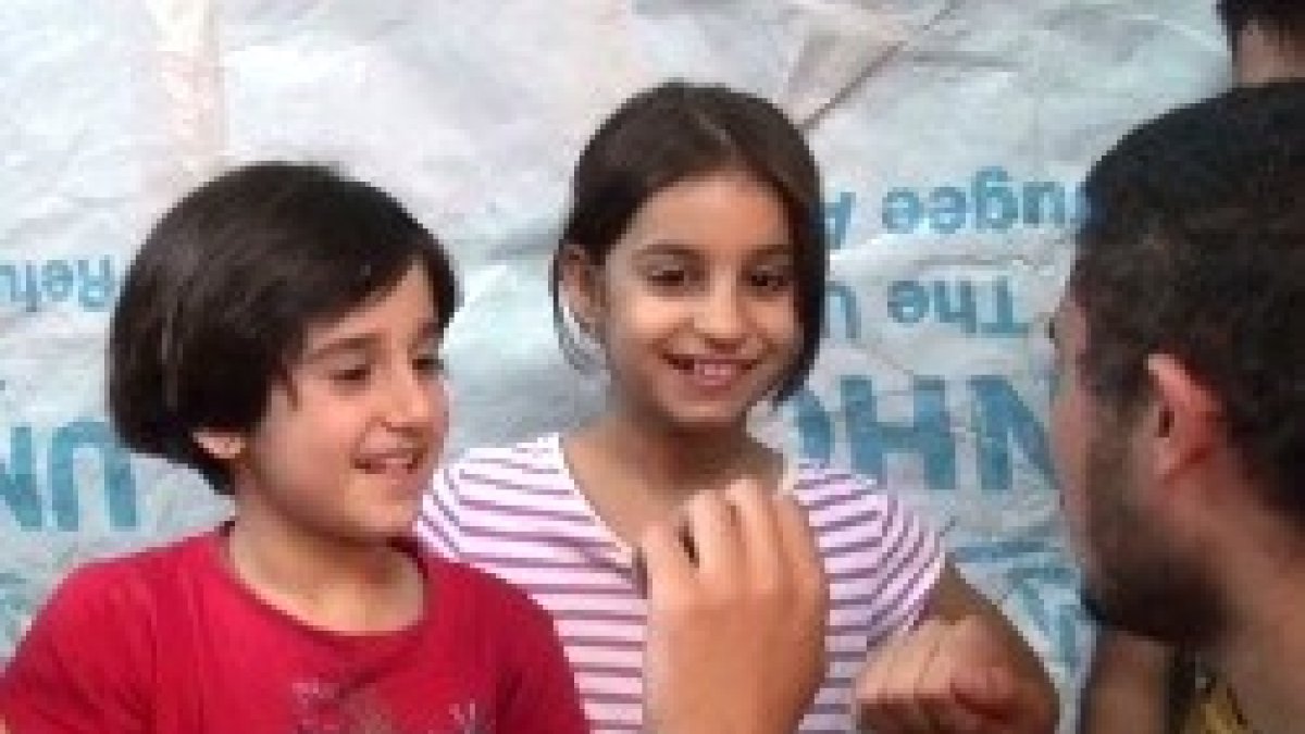 Unas niñas cristianas iraquíes desplazadas enseñan a contar hasta diez en árabe a un voluntario de CampamentoIrak