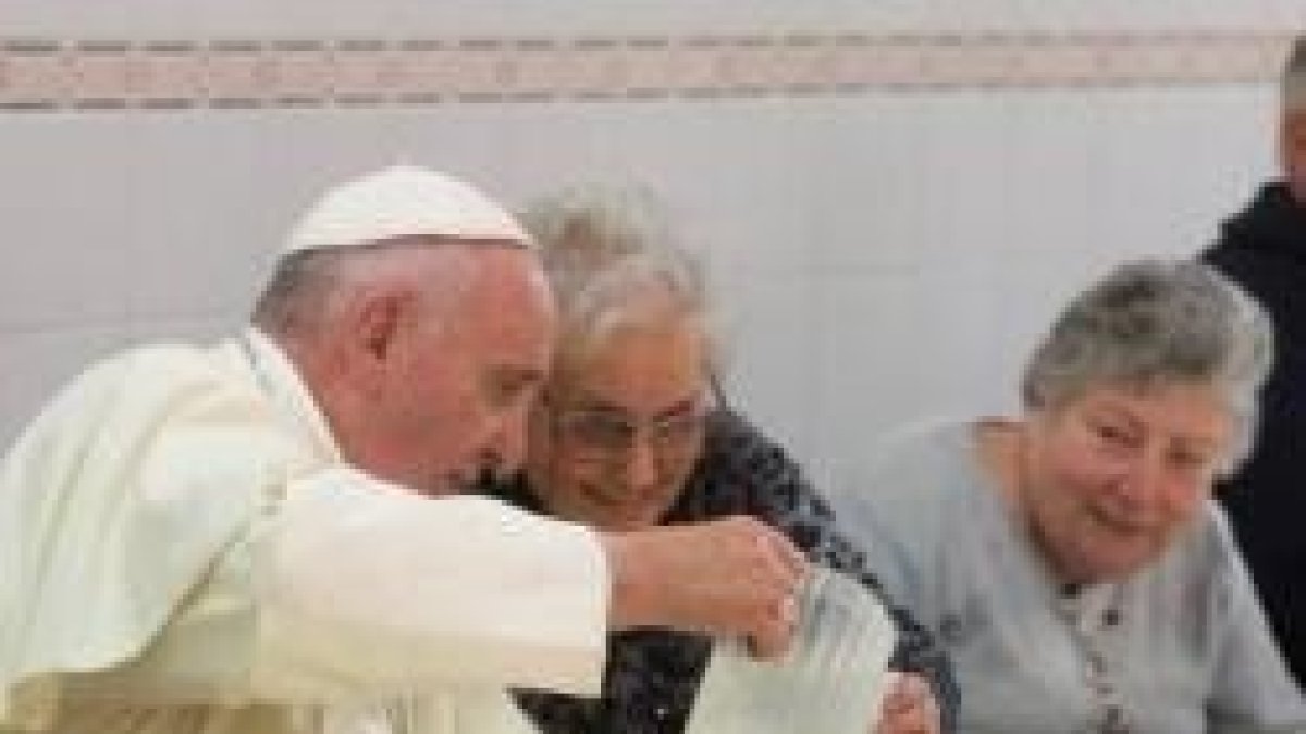 El Papa Francisco sirve el agua a una compañera de mesa en el comedor de Cáritas Florencia